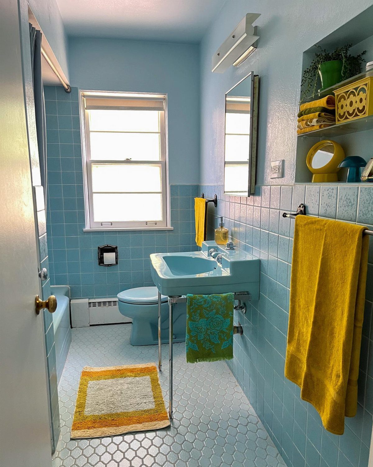 Light blue sink and toilet in a blue tiled mid-century modern bathroom.