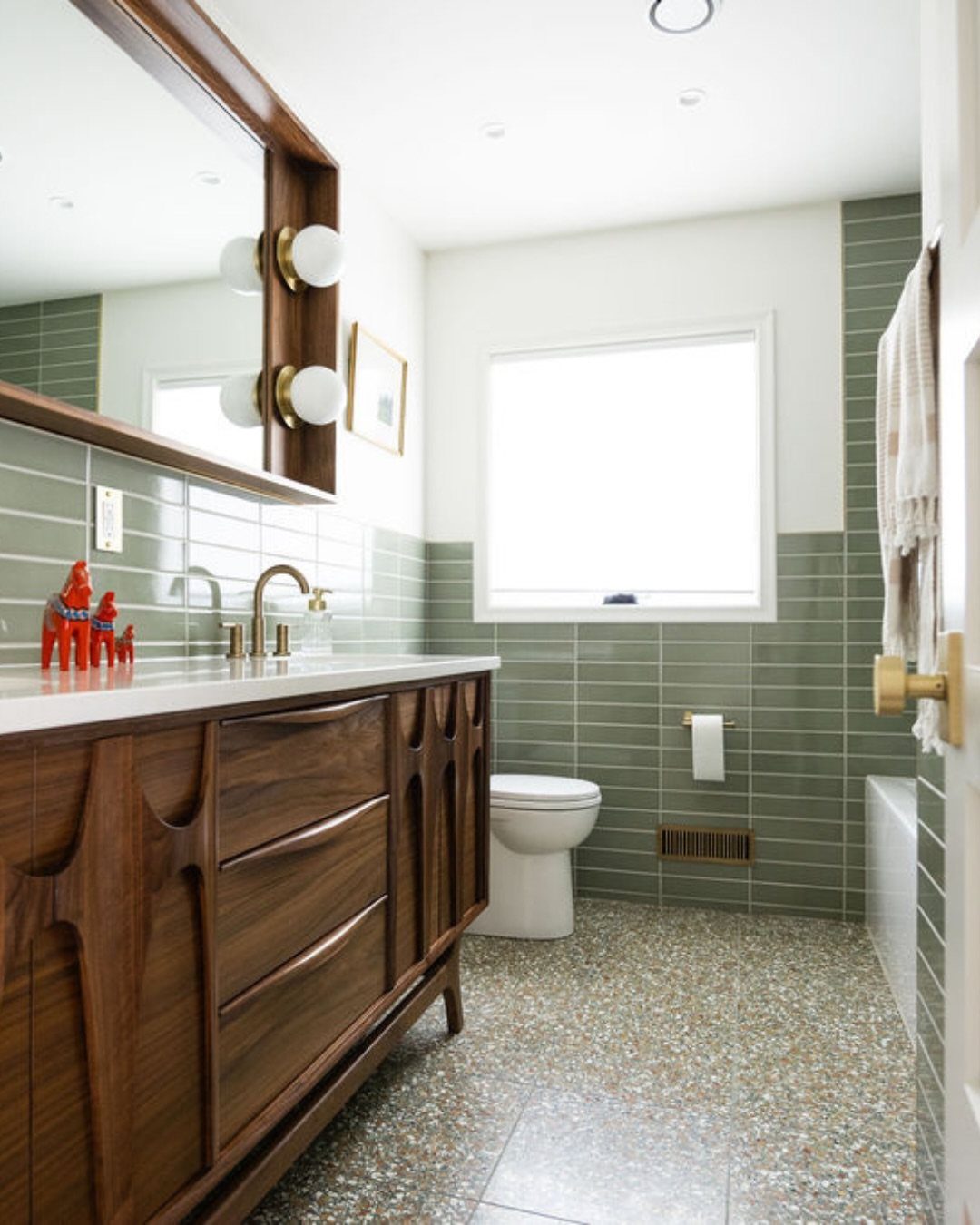 Speckled terrazzo flooring in a mid-century modern bathroom with a wood vanity.