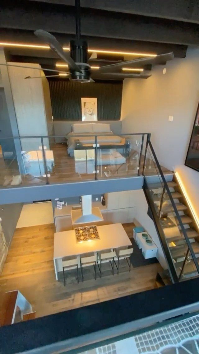 Modern loft apartment with a mezzanine bedroom overlooking a dining area and kitchen.