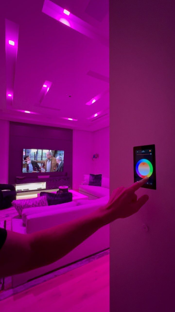 Hand adjusting a digital color wheel panel to change purple room lighting.