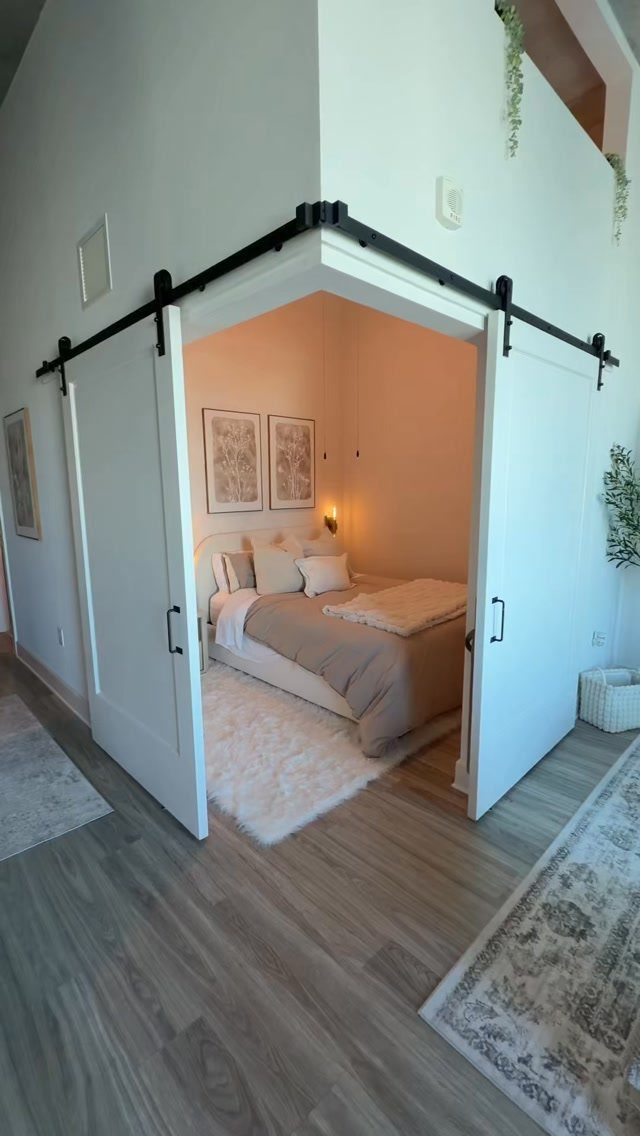 Bedroom with white sliding barn doors, beige bedding, and framed wall art.