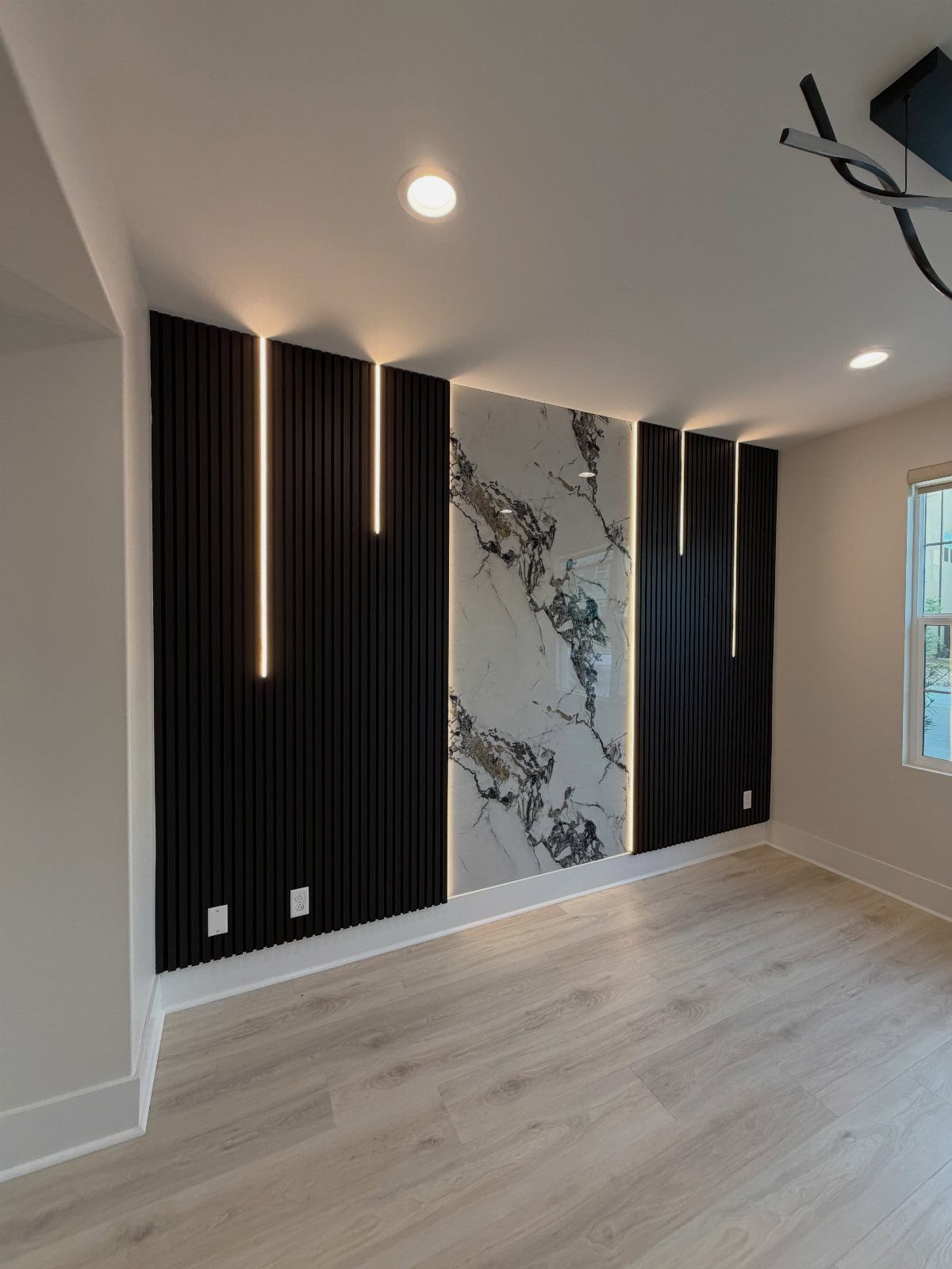 Modern accent wall with black vertical slats, LED lighting, and a marble center panel.