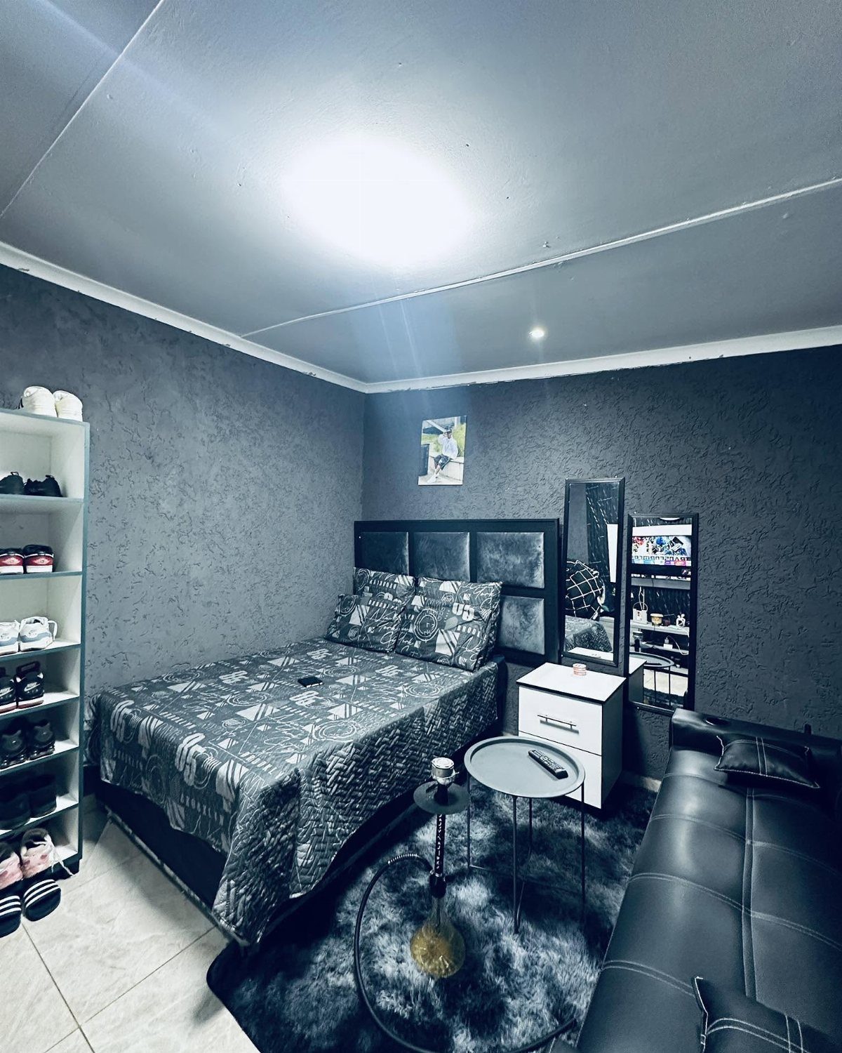 Grey and black studio apartment interior with matching bedding, rug, and walls.