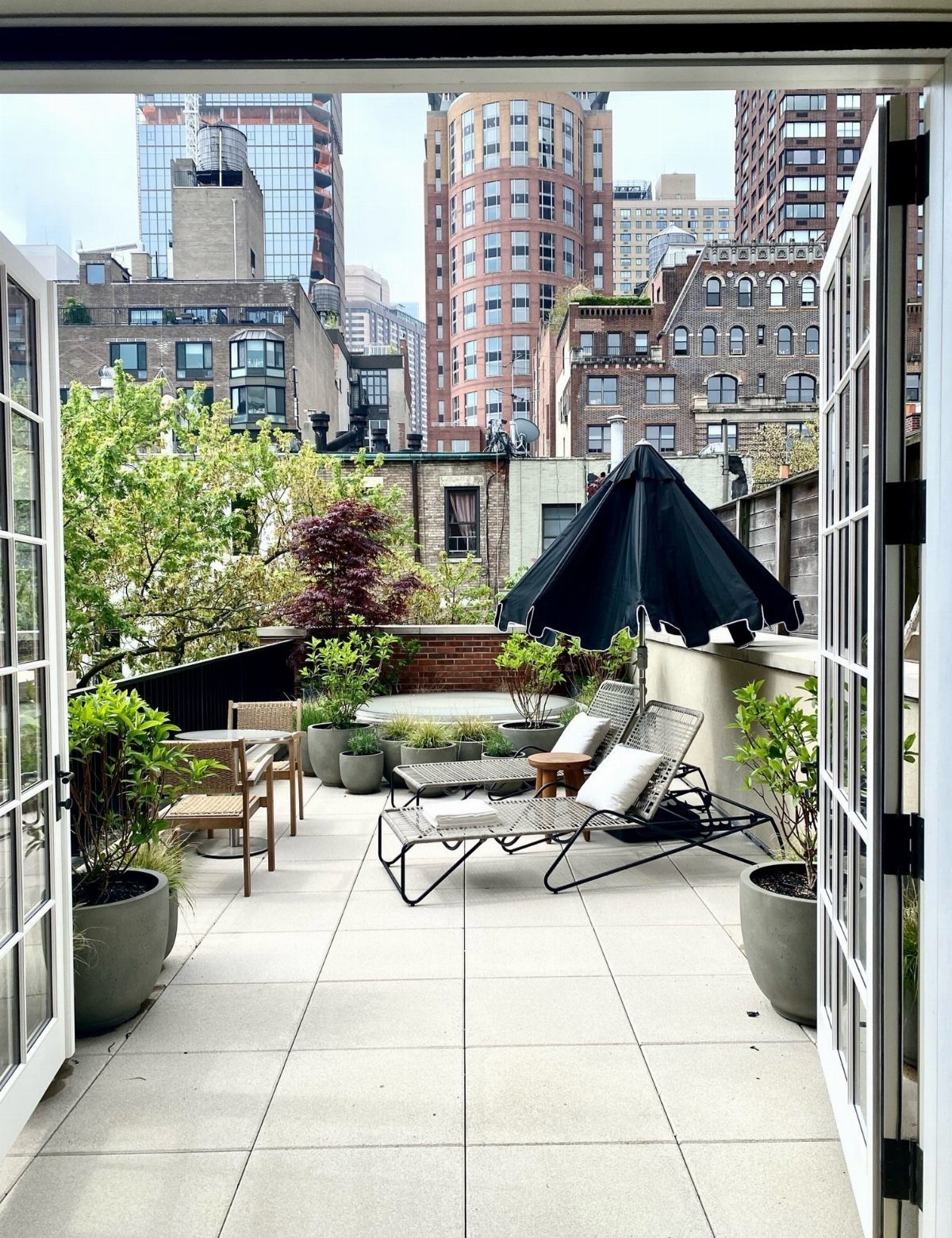 Rooftop terrace with lounge chairs and plants overlooking New York City skyscrapers