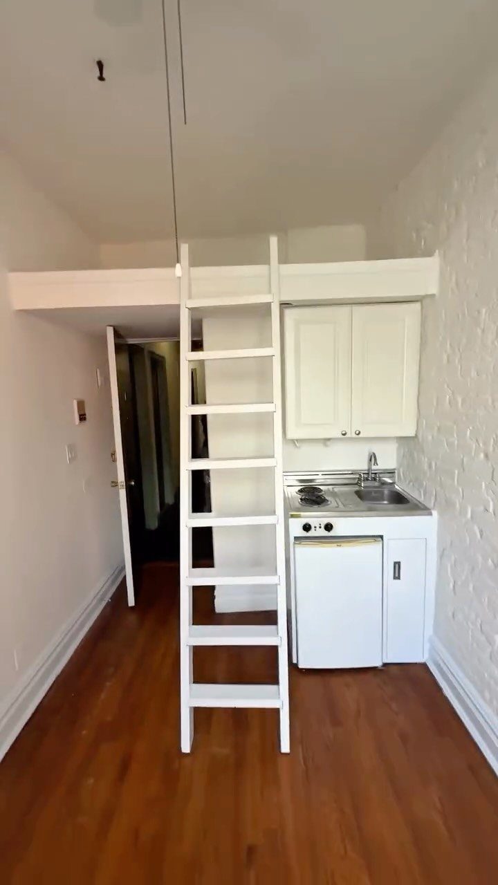 Small studio apartment with a compact kitchenette and a lofted bed area.