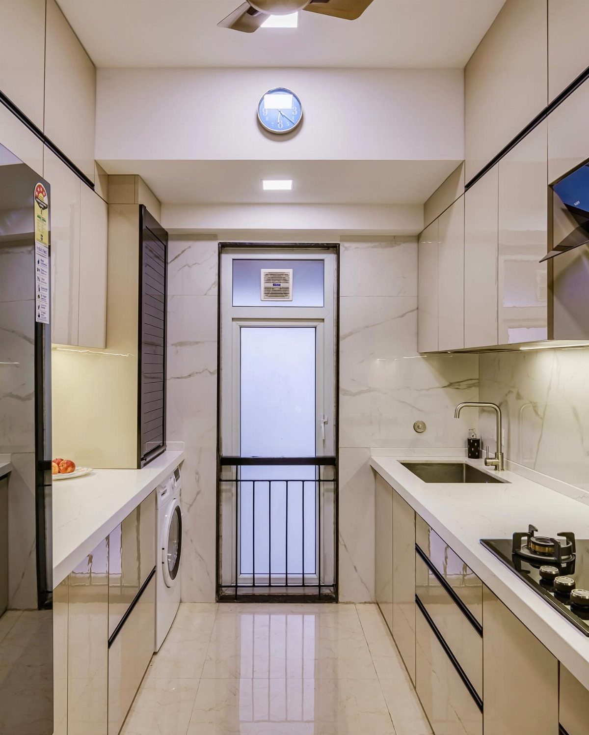 Narrow modern galley kitchen with white countertops and beige cabinetry in small apartment