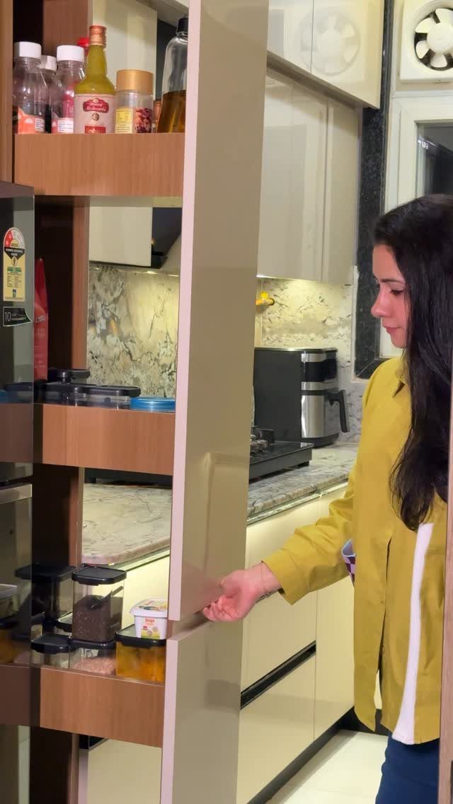 Woman opening a slim pull-out pantry shelf in a modern, compact kitchen.