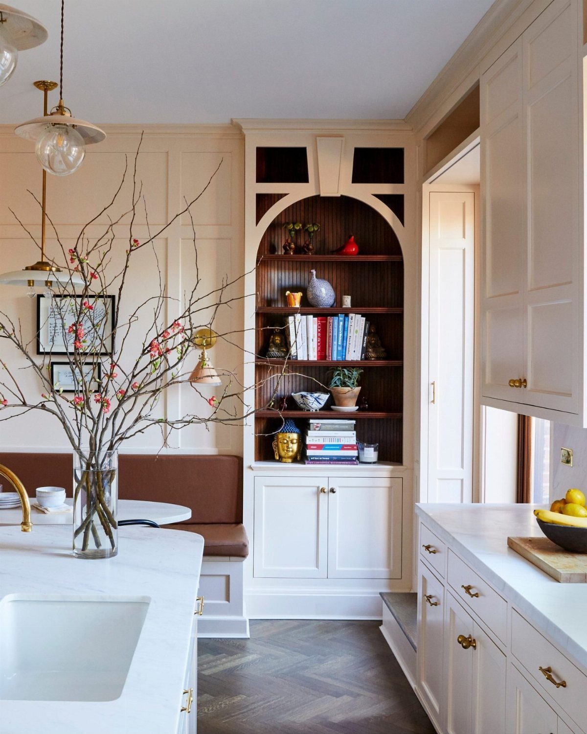 Built-in arched bookshelf and leather banquette in a bright white kitchen area.