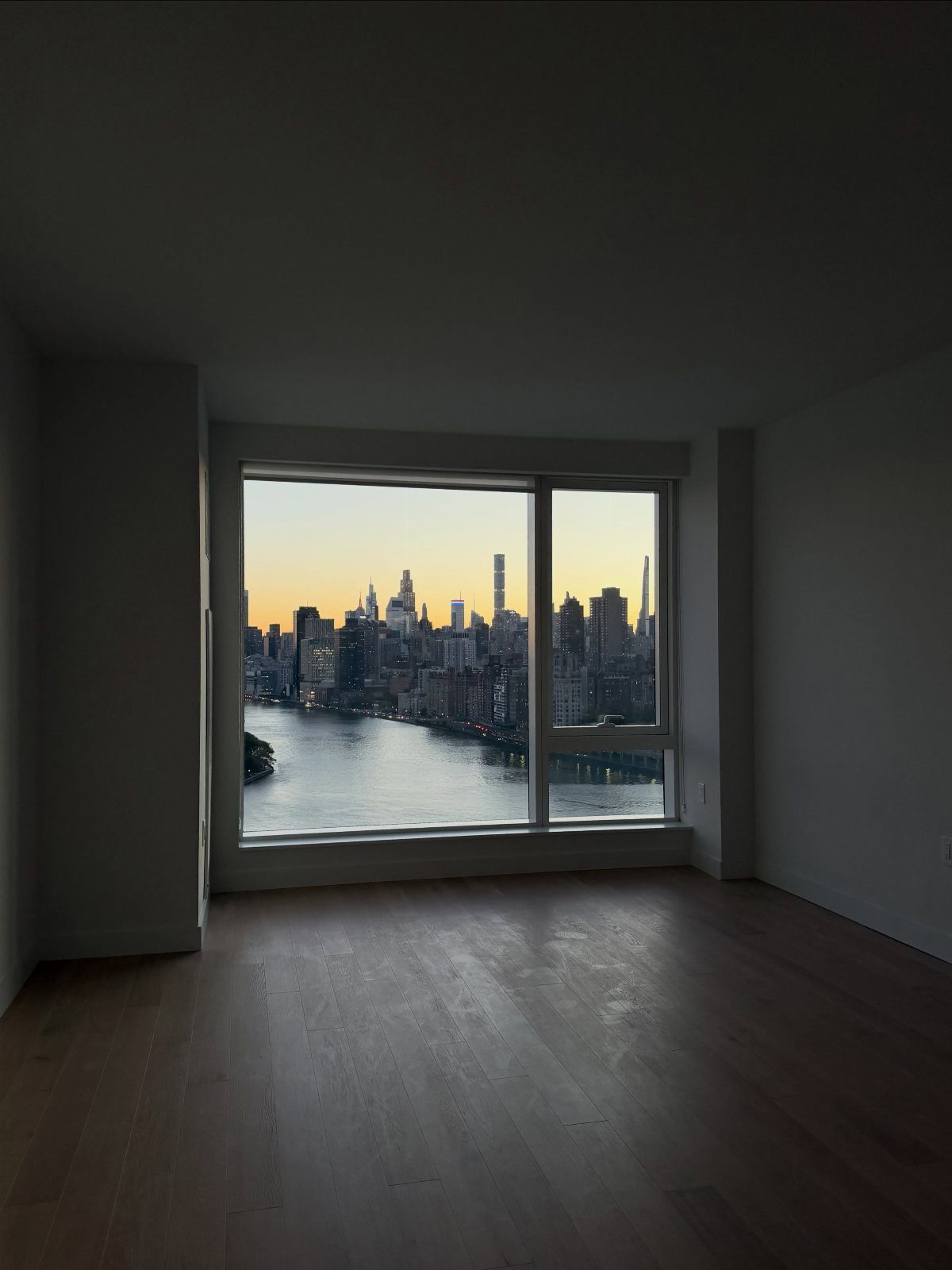 Empty room with a large window overlooking the Manhattan skyline and East River.