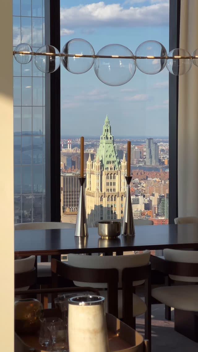 Dining room with a large window overlooking the New York City skyline and Woolworth Building.