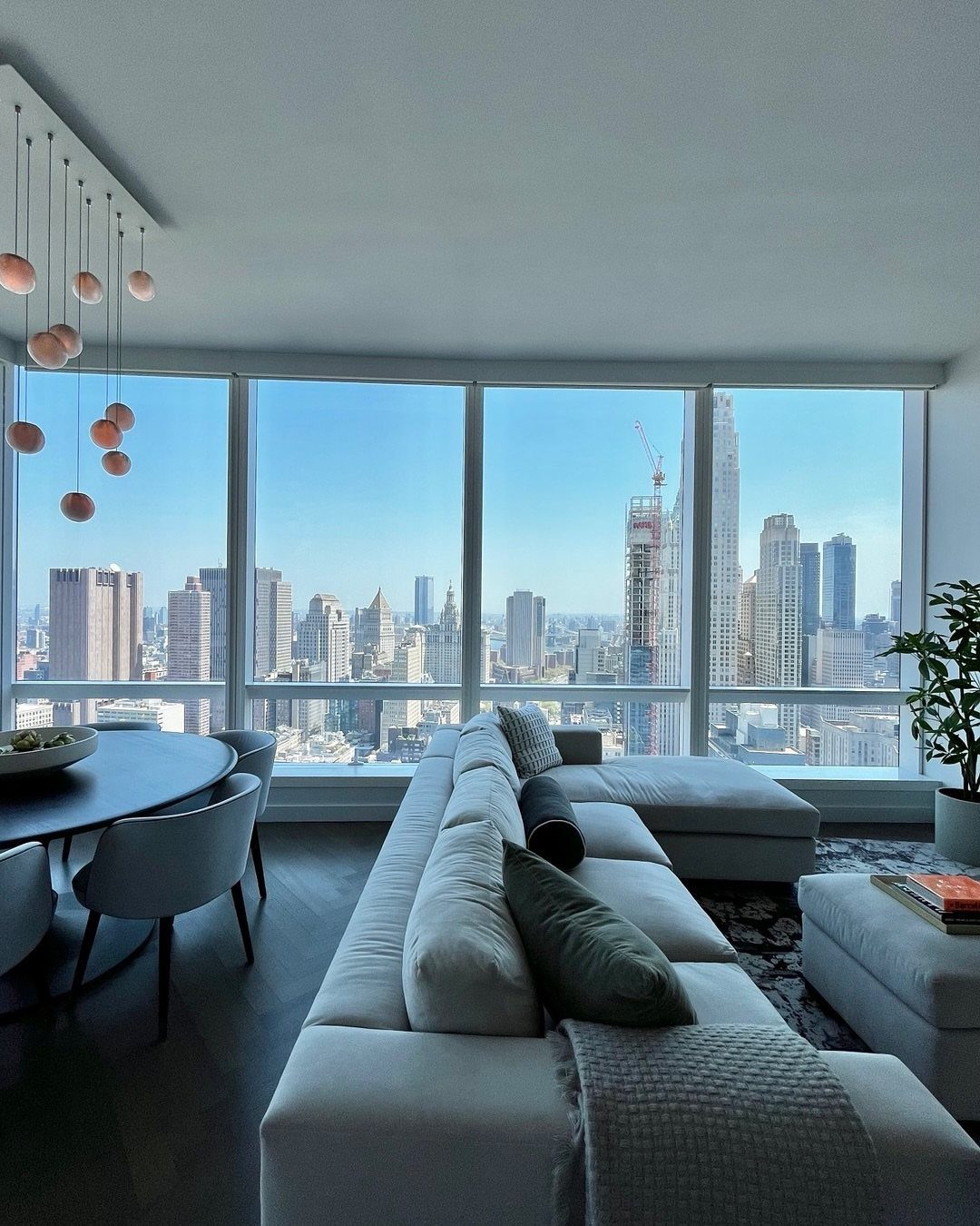 Modern apartment interior with floor-to-ceiling windows overlooking the Midtown Manhattan city skyline.