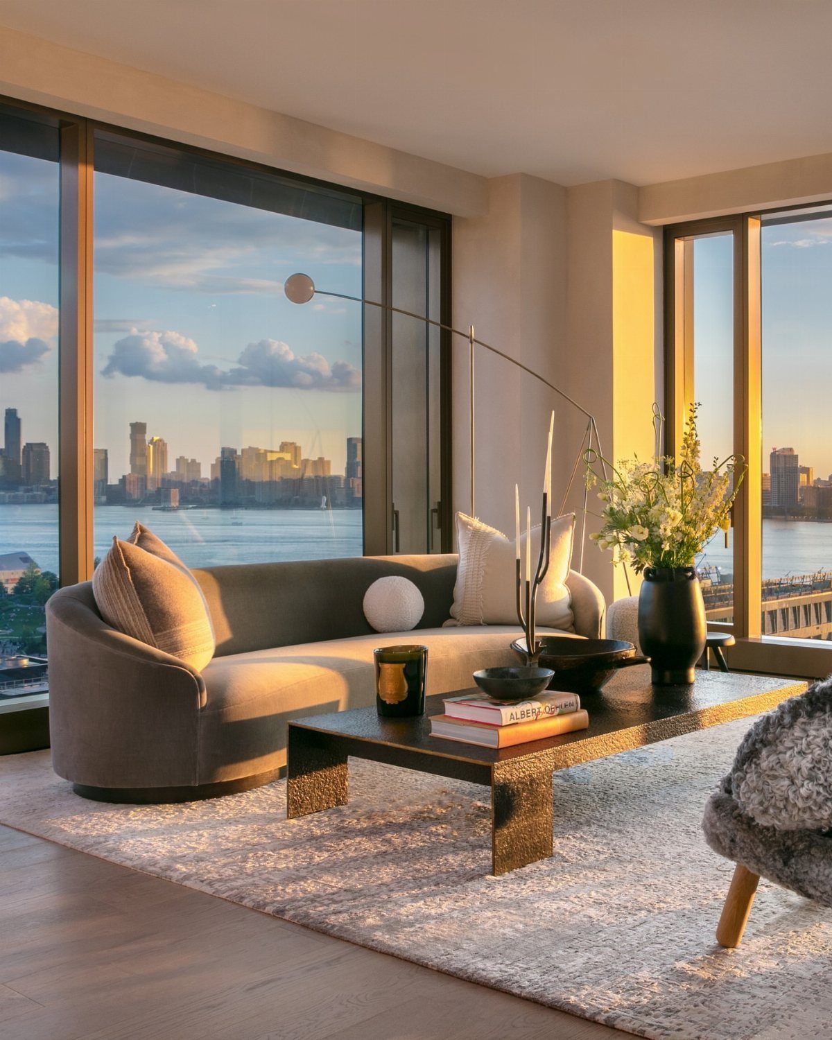 Modern living room with large windows overlooking a city skyline across the water.