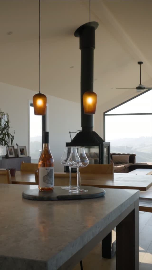 Modern home interior with concrete counters, amber pendant lights, and black wood-burning stove.