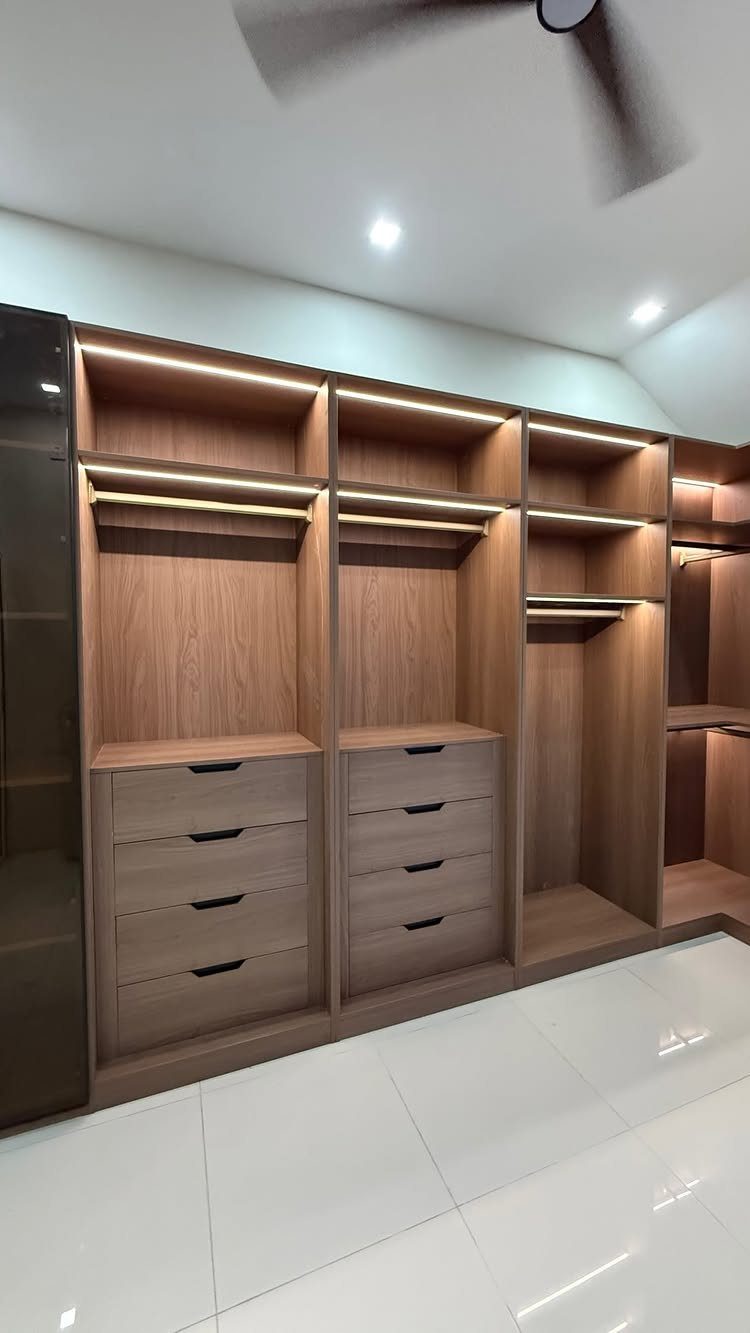 Built-in wooden wardrobe system with open shelves, drawers, and integrated warm LED lighting.