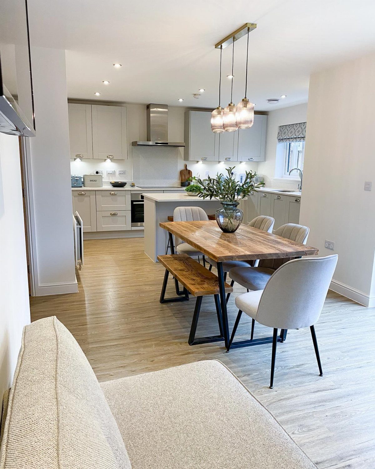 Wooden dining table with grey chairs and a bench in a studio apartment.