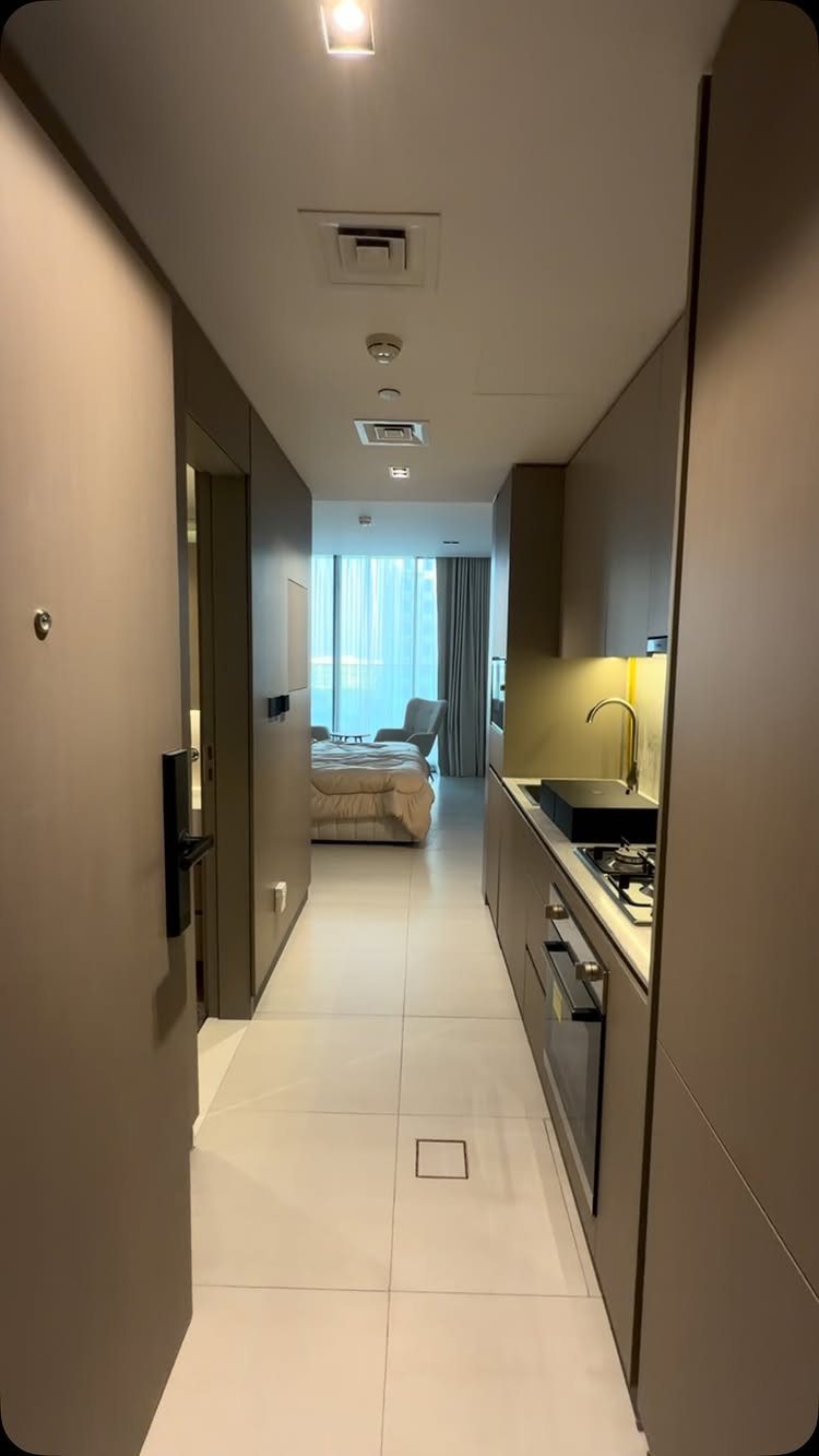 Modern studio apartment with a kitchenette leading into a bedroom area.