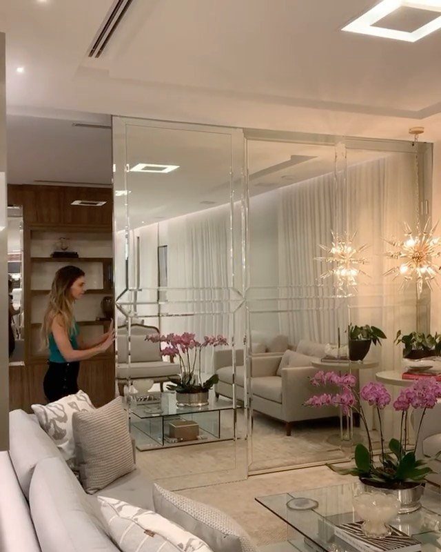 Modern living area with grey sofa, glass tables, and large mirrored sliding doors.