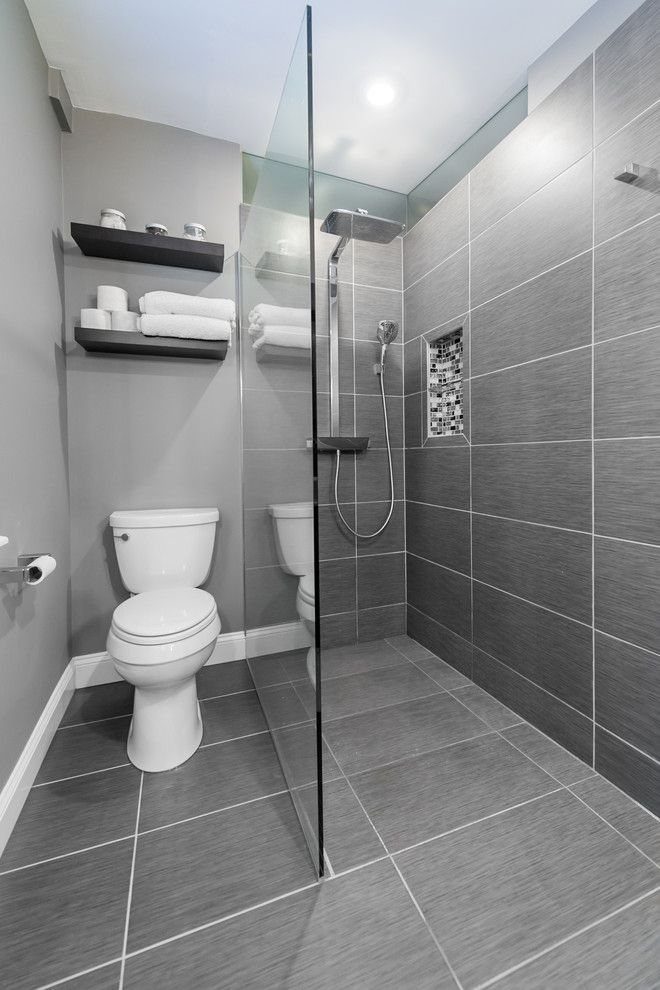 Two dark floating shelves with white towels in a grey modern bathroom.