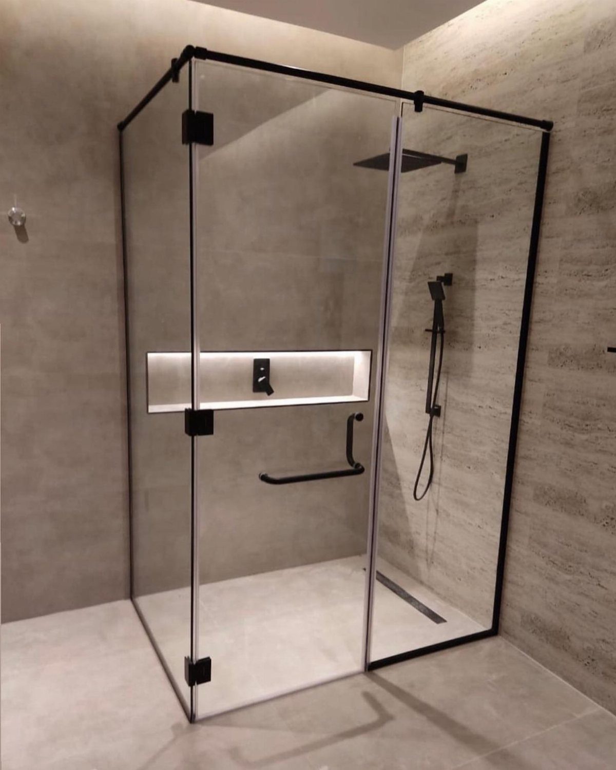 Glass shower enclosure with black frame and built-in illuminated wall niche.