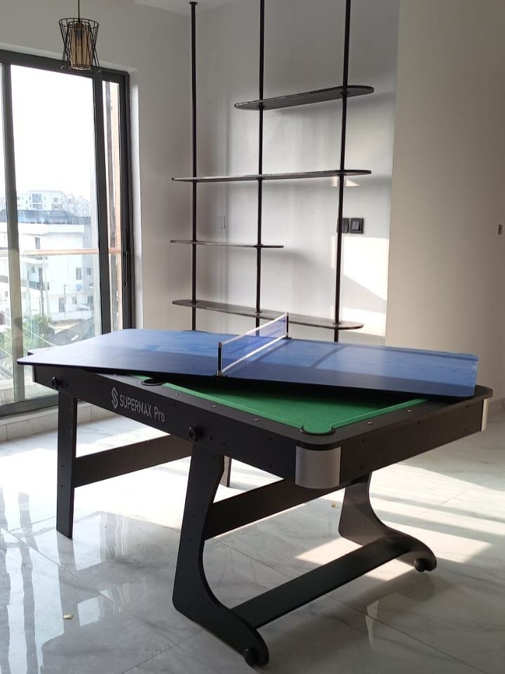 Multi-game table with pool and ping pong surfaces in a bright modern room.