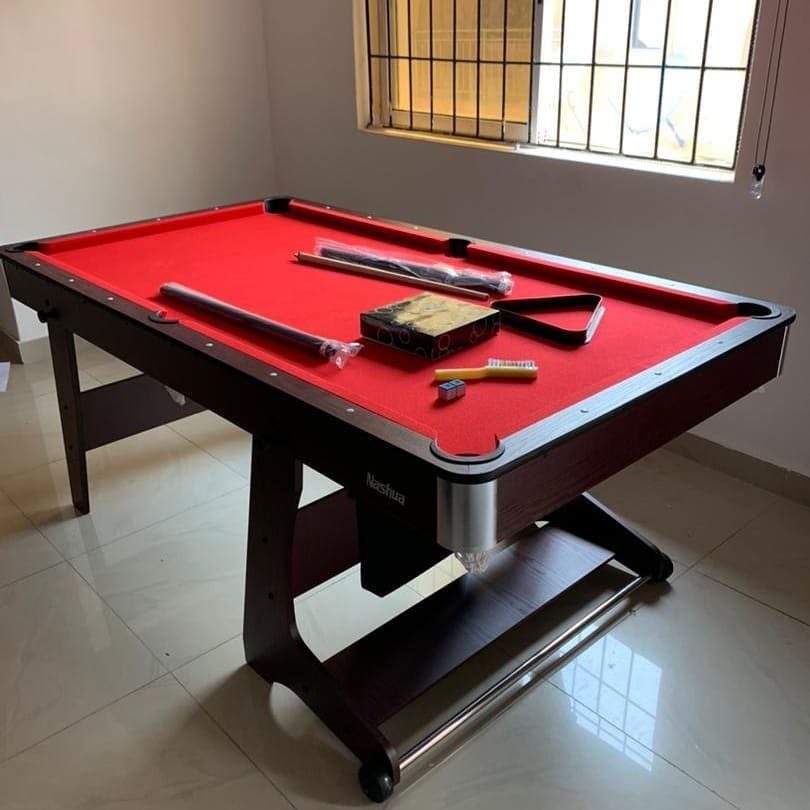 Small pool table with red felt in a compact room with white walls.