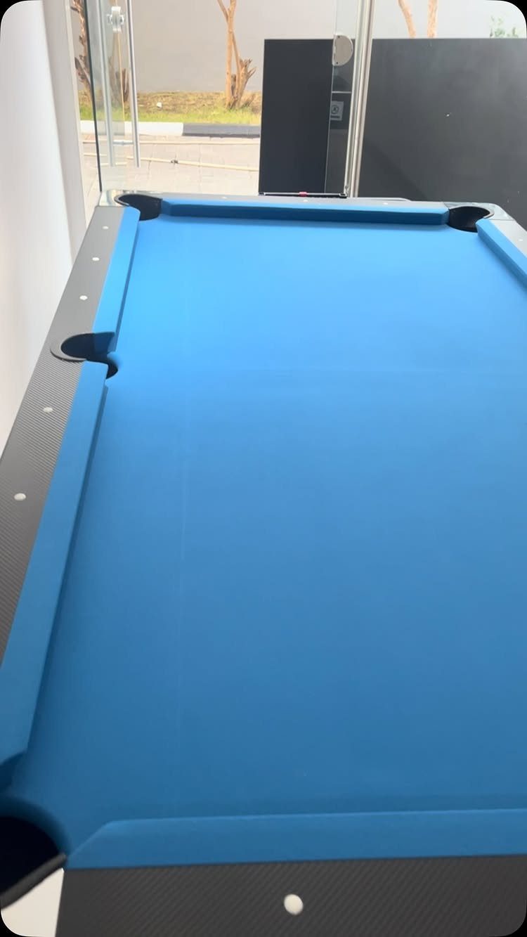 Small pool table with bright blue felt and black rails in modern room