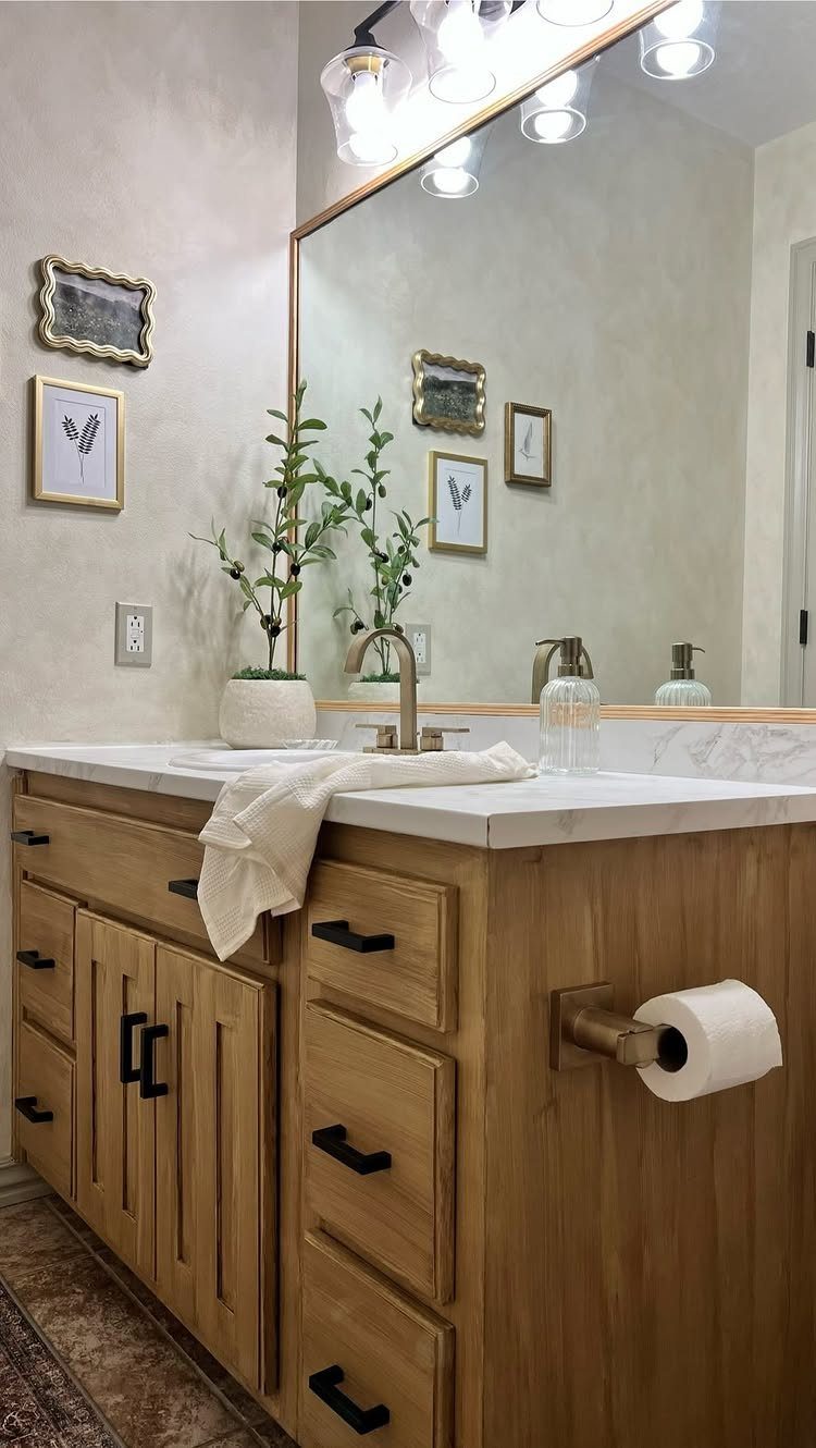 Large rectangular mirror above a light wood bathroom vanity with marble countertop.