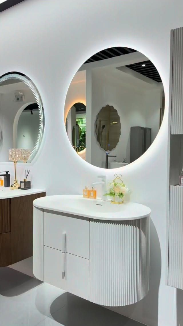 Curved white wall-mounted vanity with a large circular backlit mirror in a bathroom
