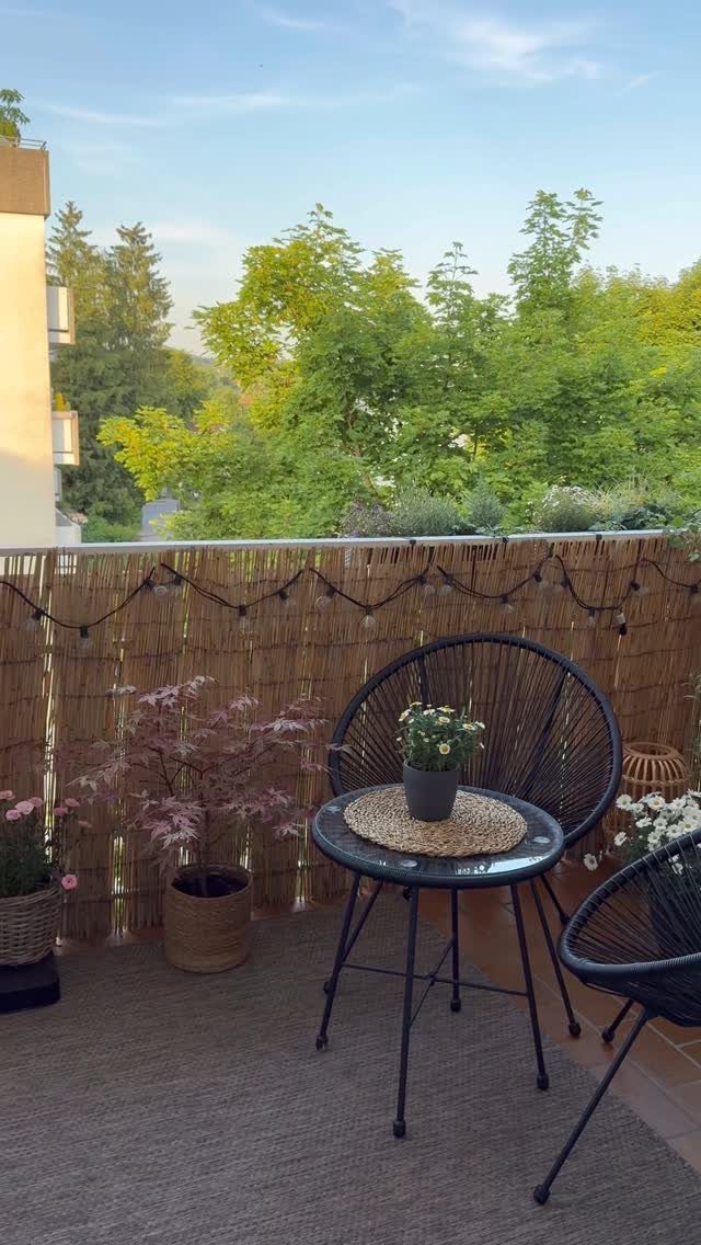 Bamboo privacy screen on a balcony with a black bistro set and plants.
