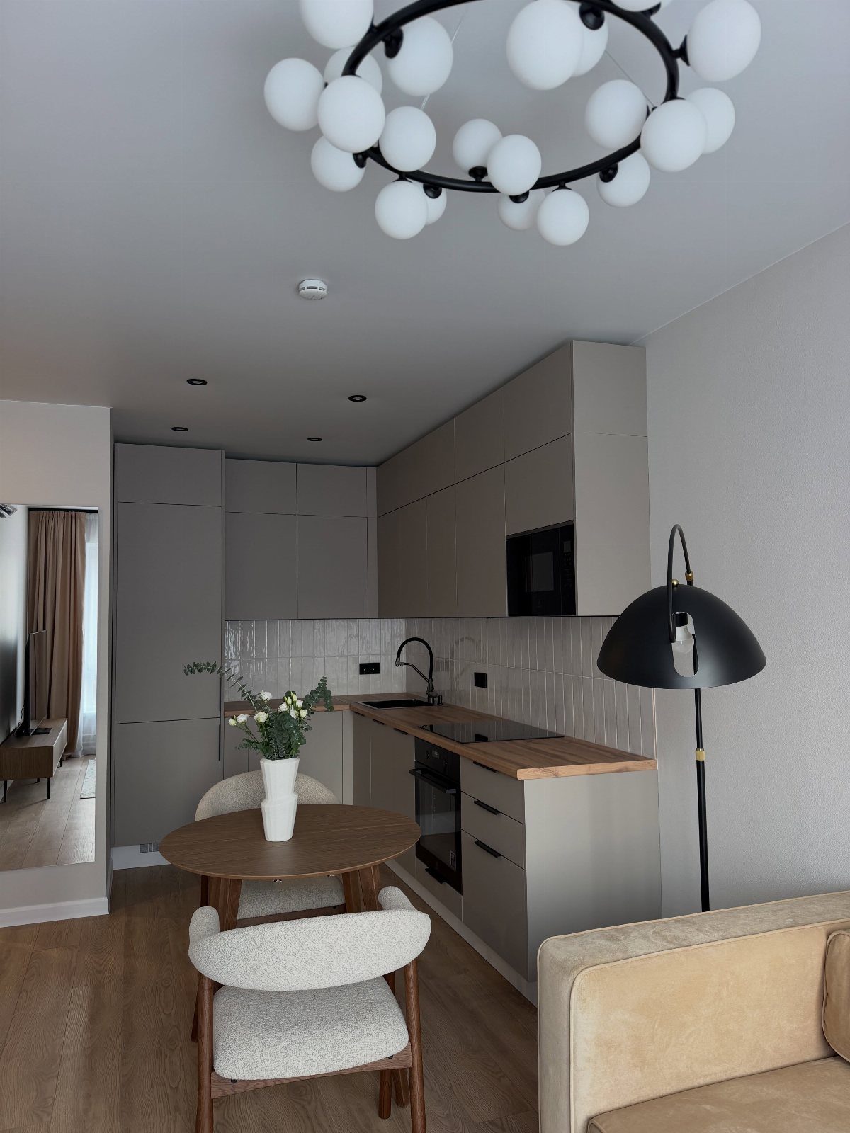 Modern small apartment interior with light grey walls, white furniture, and globe lighting.