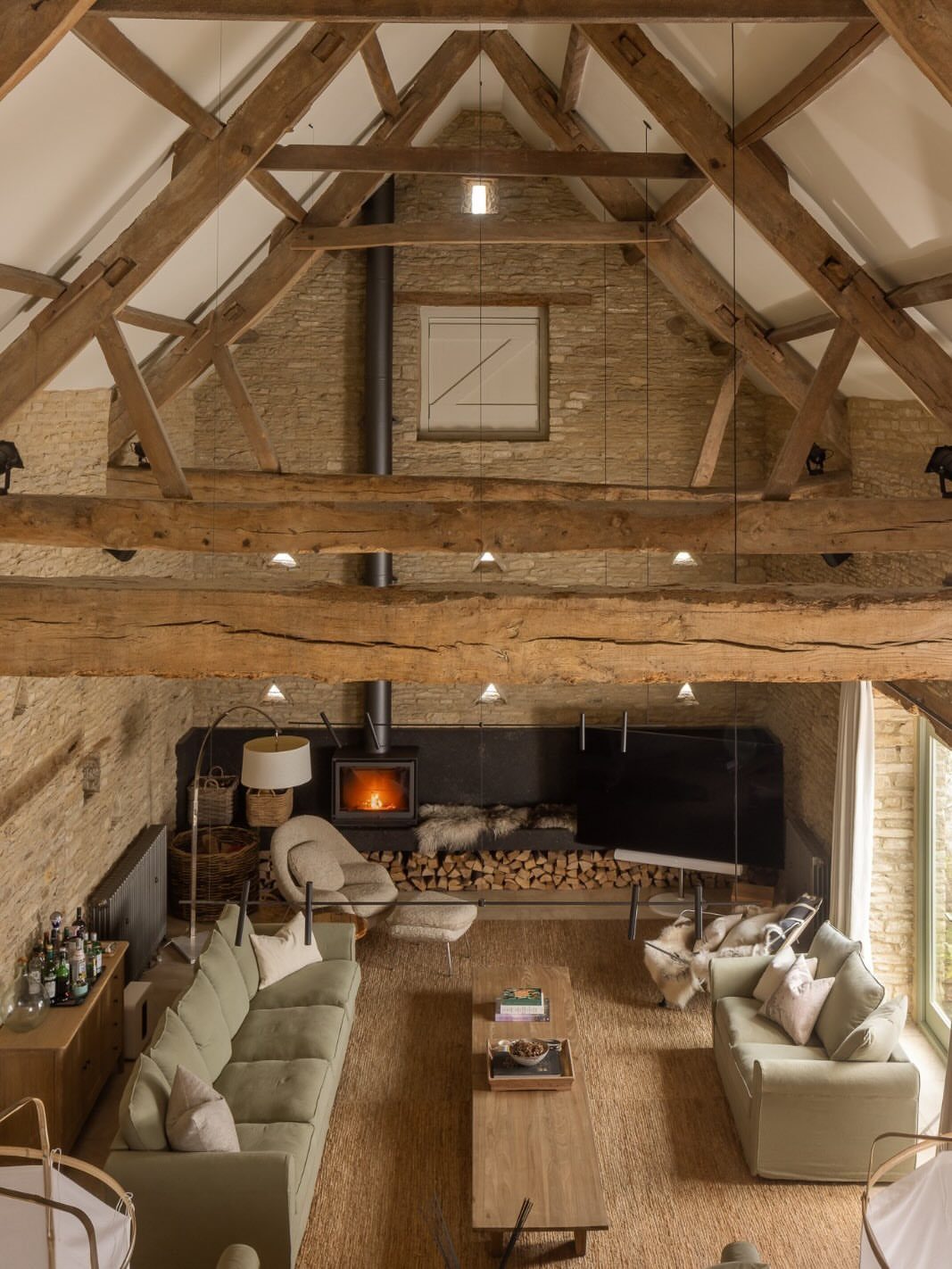 Rustic living room with exposed wooden beams, stone walls, and a cozy fireplace.