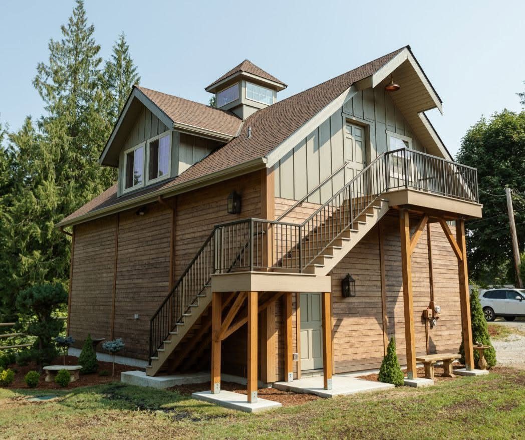 Wooden barn building with external stairs leading to a second floor balcony.