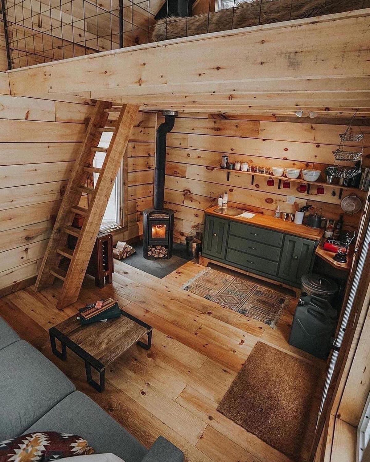 Rustic wooden barn apartment interior with a small kitchen and loft ladder.
