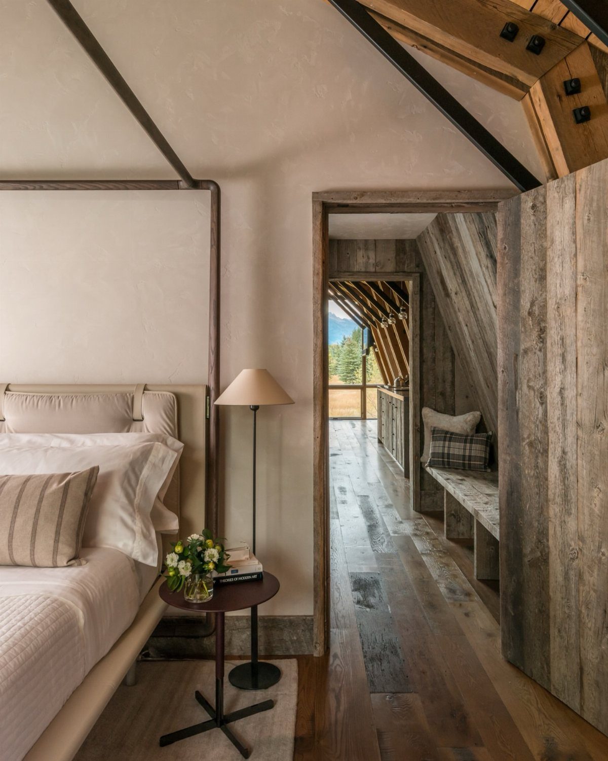 Rustic loft bedroom with a bed, wooden floors, and weathered wood walls.