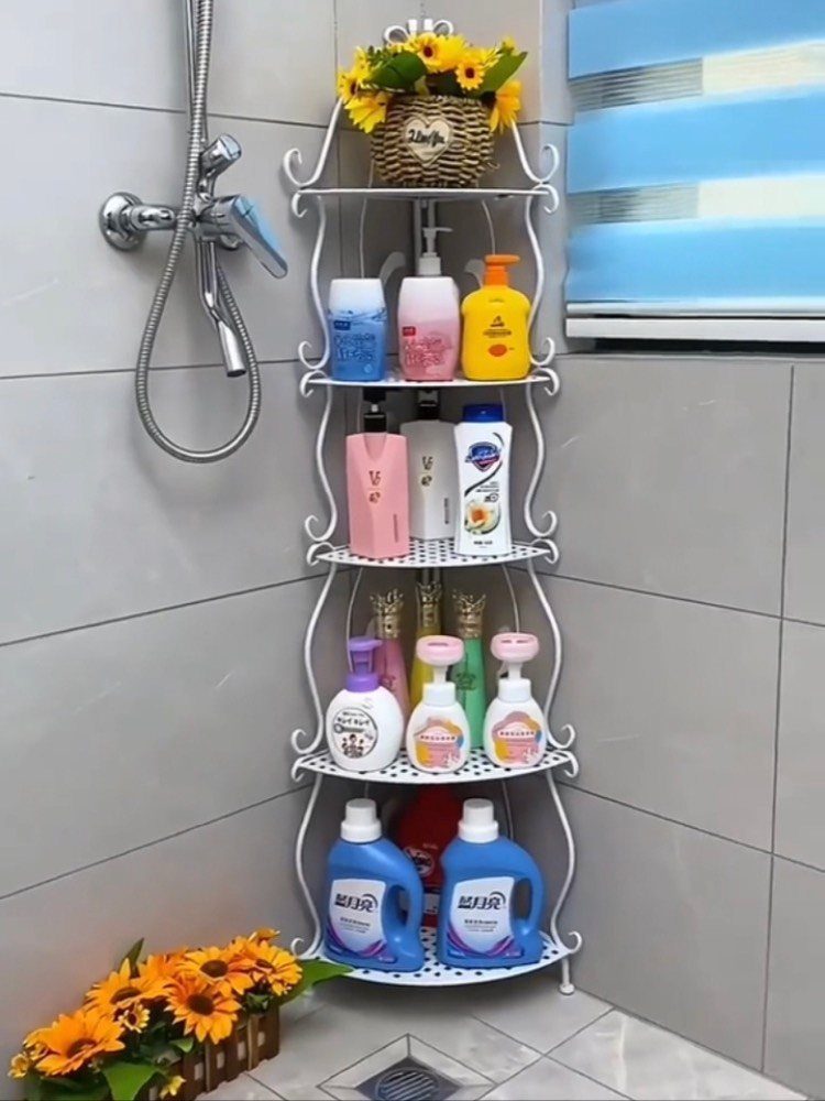 White corner shelving unit holding colorful bathroom bottles and sunflowers against grey tiles.