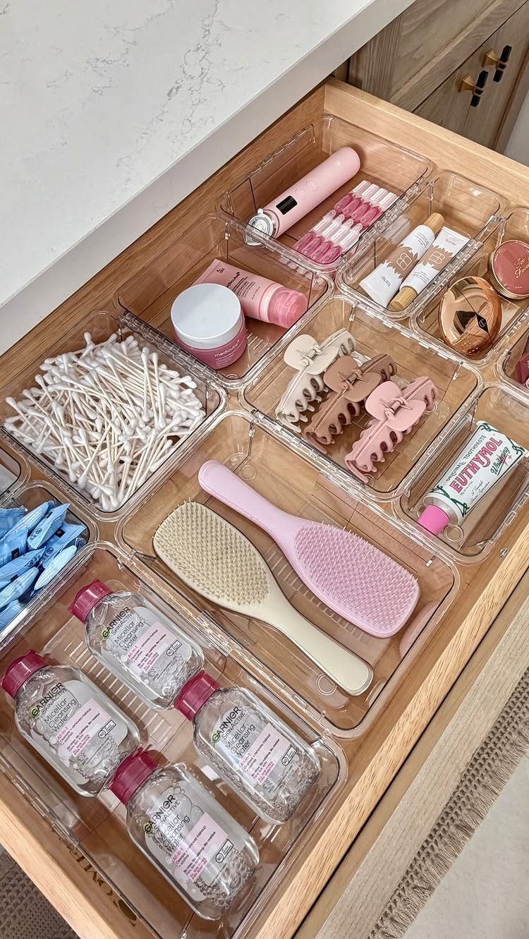 Clear acrylic drawer organizers holding beauty tools and skincare in a wooden drawer.