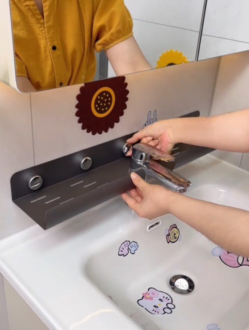 Black metal organizer shelf being installed over a white bathroom sink faucet