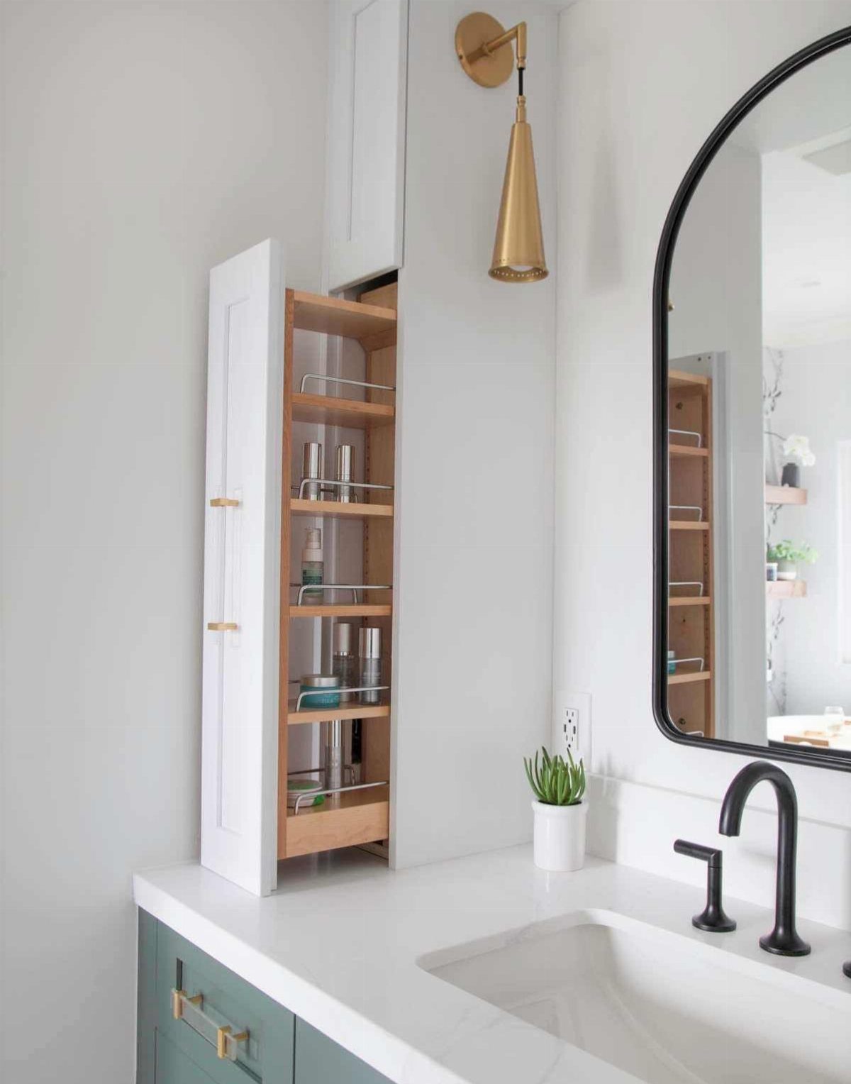 Pull-out wooden cabinet organizer with toiletries next to a white bathroom sink.