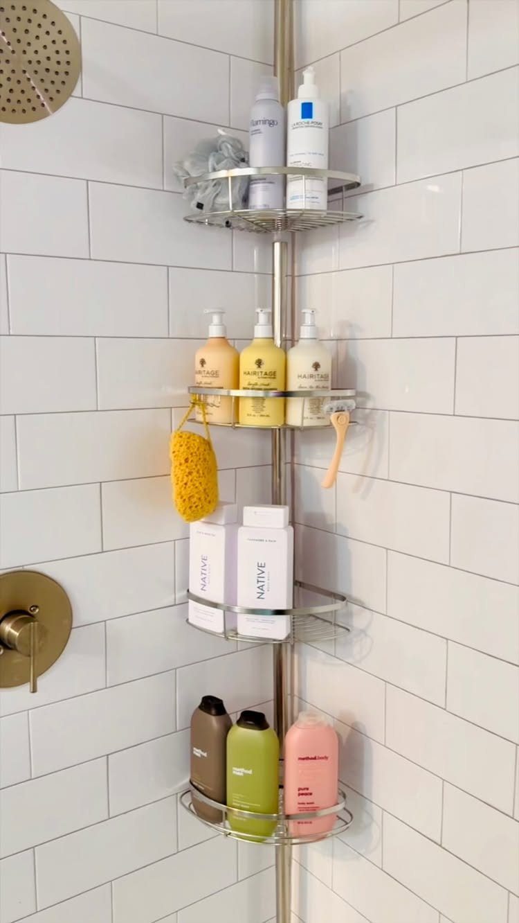 Metal corner shower caddy holding various toiletries against white subway tile walls.