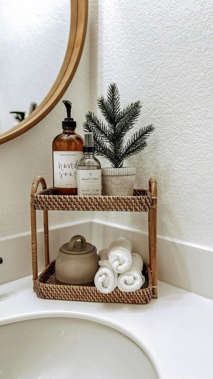 Woven rattan organizer holding soap, a small plant, and rolled towels on a counter.