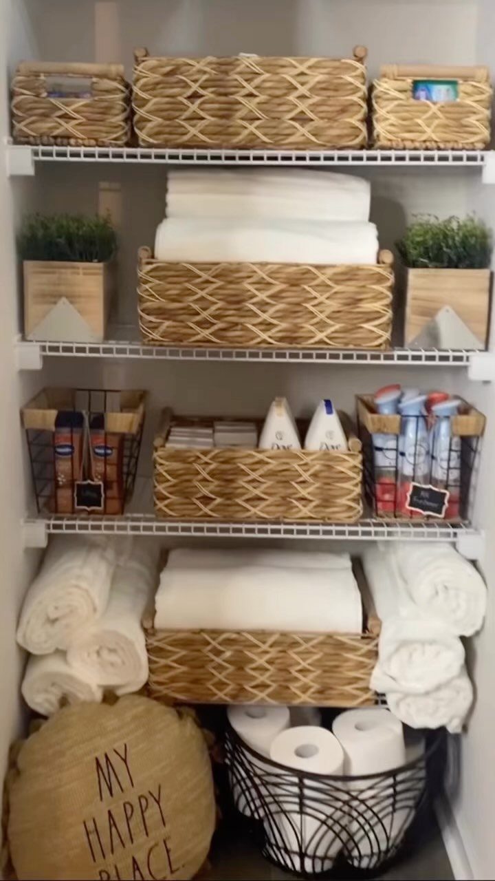 Woven wicker baskets and wire bins organizing towels and toiletries on white shelving.