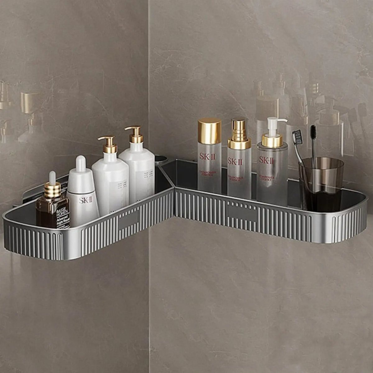 Silver metal corner shelf holding skincare bottles and toothbrushes on a marble wall.