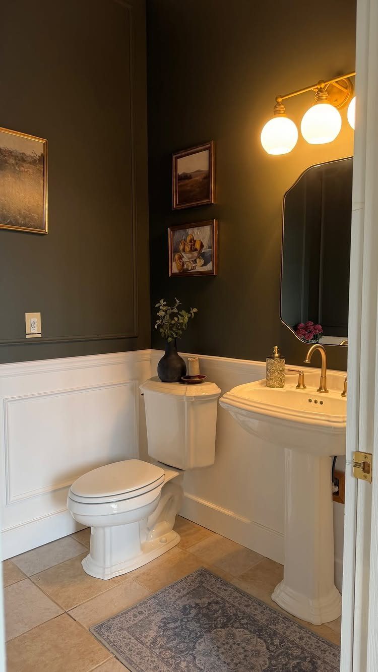Small bathroom with dark olive green walls, white wainscoting, and gold fixtures.
