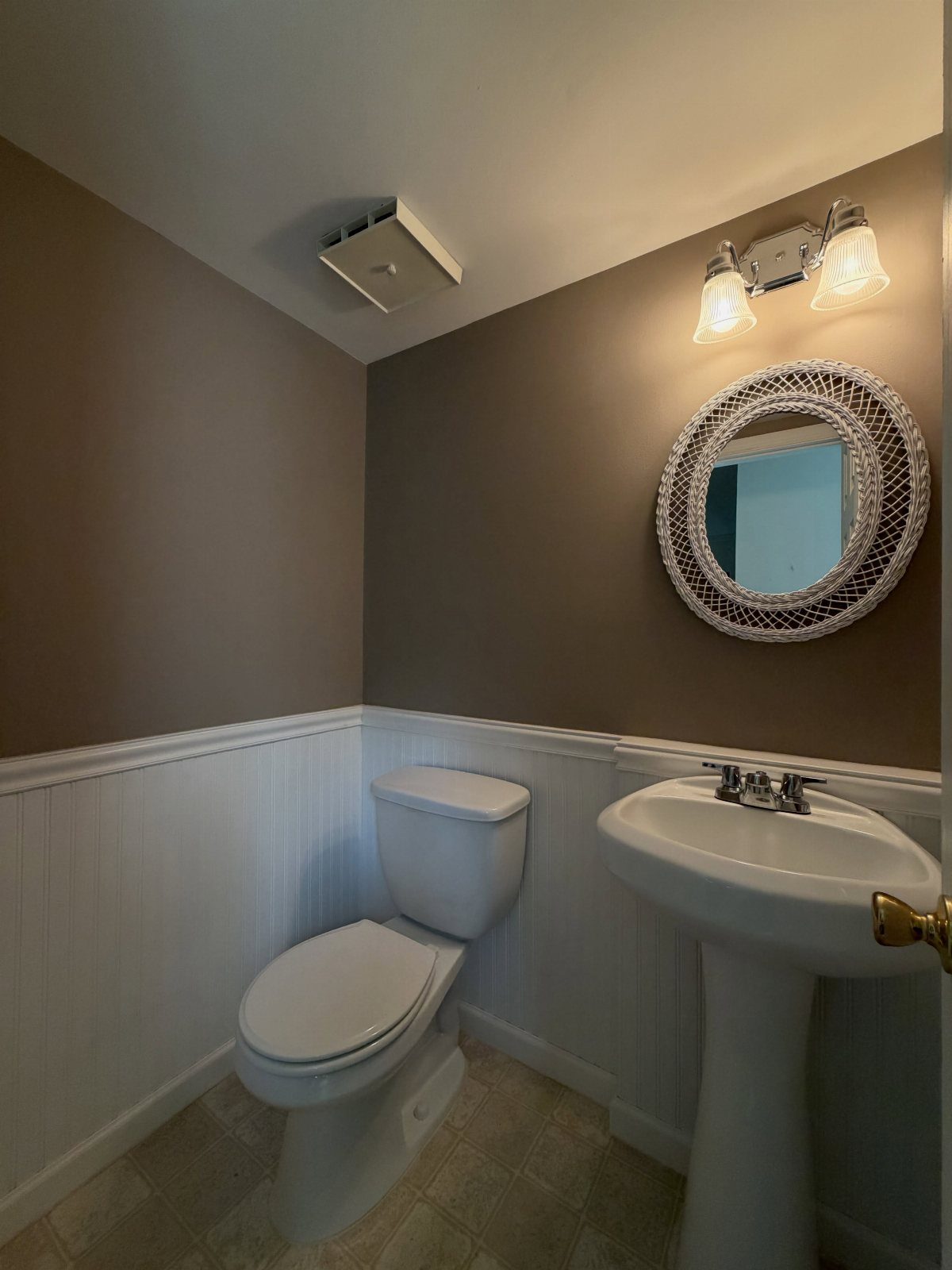 Taupe upper walls and white wainscoting in a small bathroom with pedestal sink.