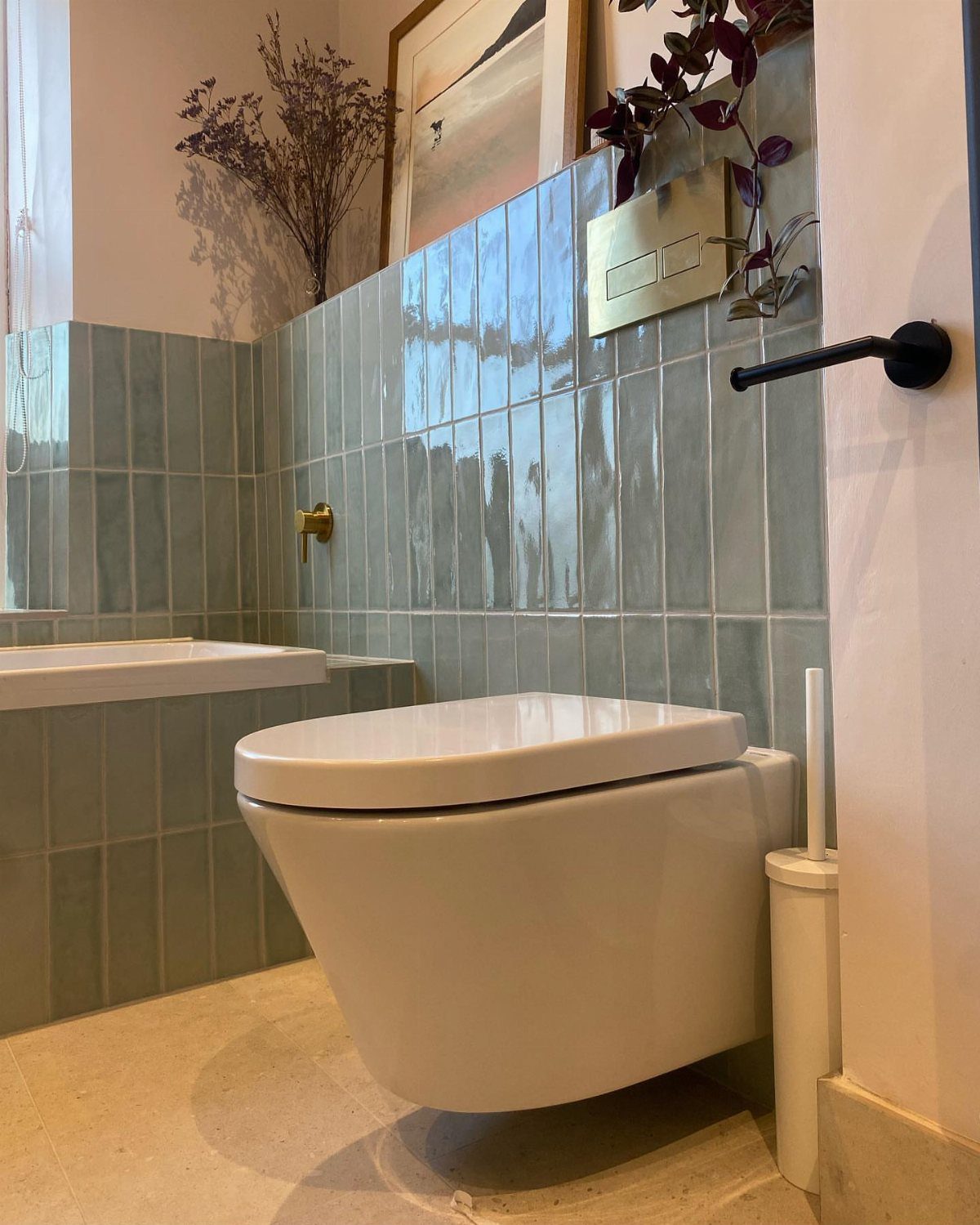 Wall-hung white toilet with gold fixtures against light blue tiled bathroom walls.