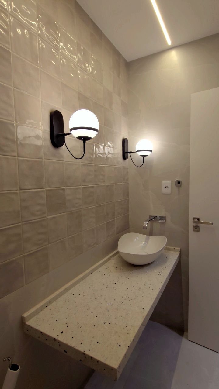 White vessel sink on floating counter with wall sconces and recessed ceiling lighting