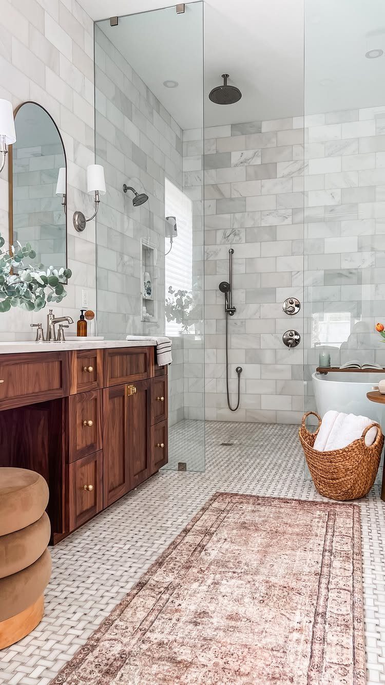 Curbless walk-in shower with frameless glass and white marble tiles in a bright bathroom.