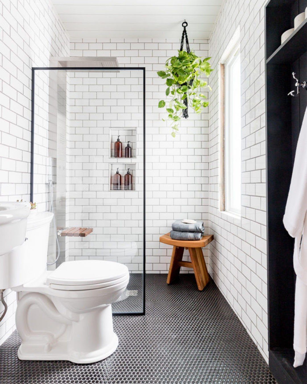 Small bathroom with white subway tiles, black floors, and a glass shower enclosure.