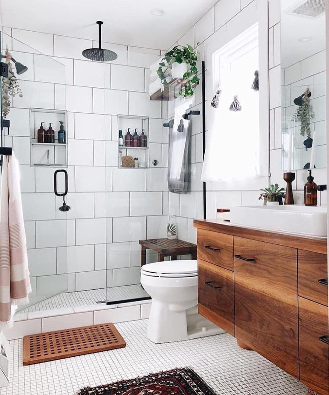 White rectangular wall tiles in a small bathroom with a wooden vanity and toilet.