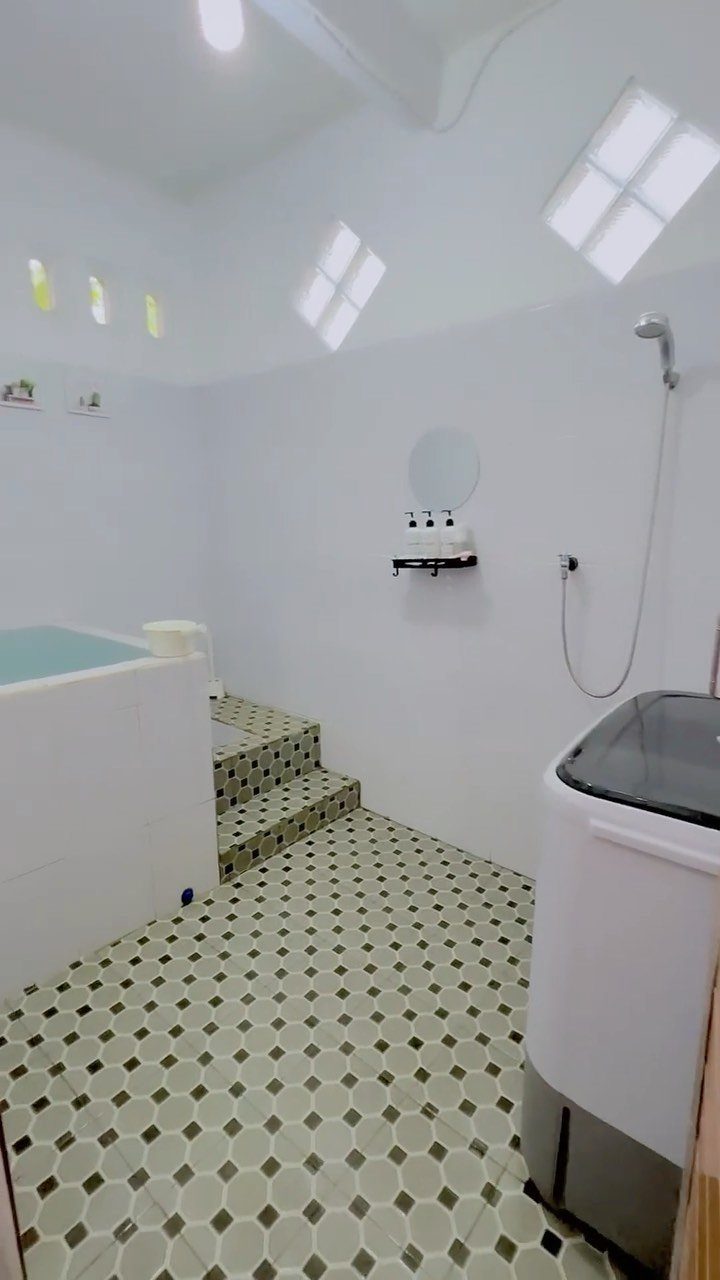 Small white bathroom with a built-in bathtub and green diamond tiled floor.